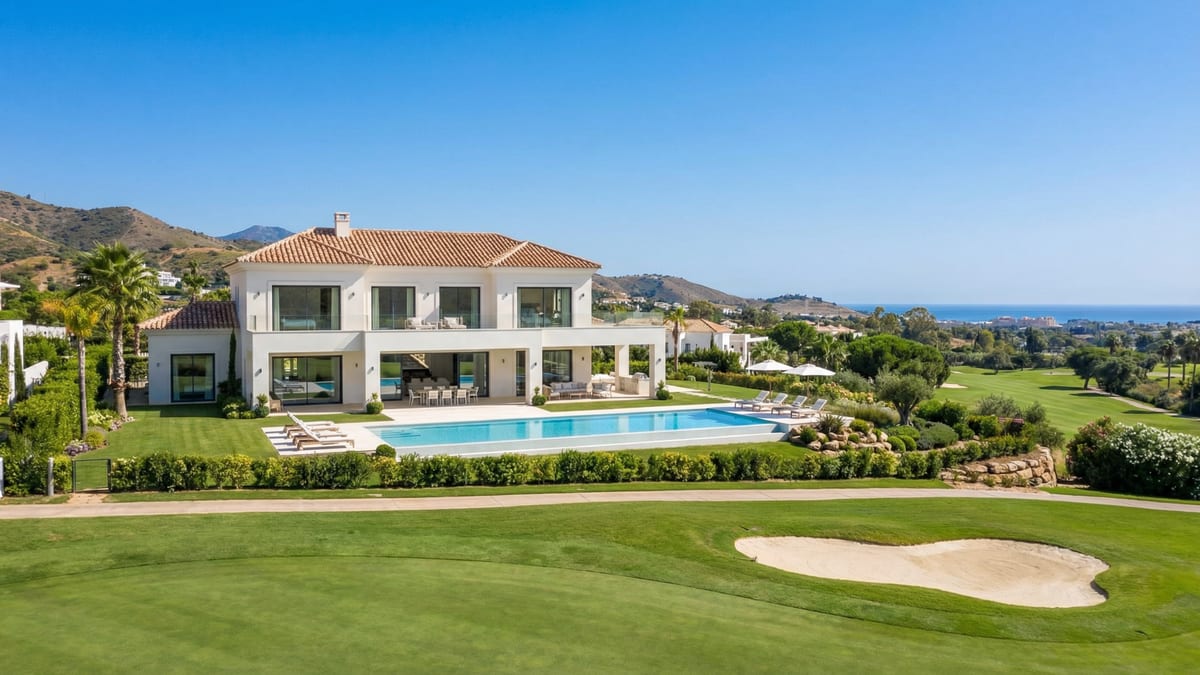 Eine moderne mediterrane Villa an der Costa del Sol mit eleganter Architektur, üppigen Gärten und einer ruhigen Außenterrasse unter einem strahlend blauen Himmel.